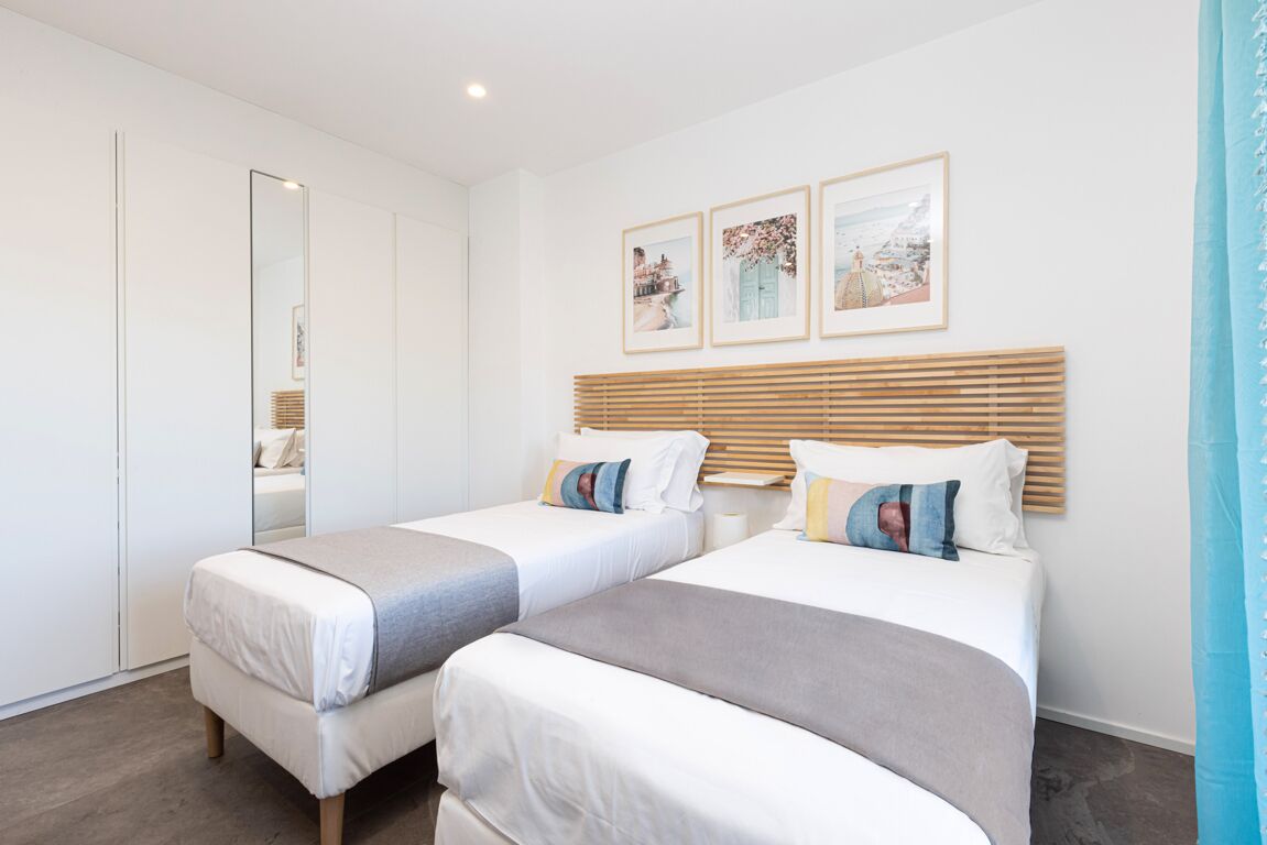 Une chambre d’hôtel avec deux lits, un grand miroir et trois tableaux encadrés accrochés au mur.