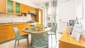 A modern kitchen with wooden cabinets, a dining table with chairs, and a breakfast setup. - New Family 3 Bedrooms House In Sorrento (Sorrento)