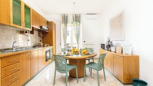 A modern kitchen with wooden cabinets, a round dining table, and green chairs. - New Family 3 Bedrooms House In Sorrento (Sorrento)
