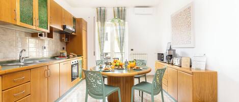 A modern kitchen with wooden cabinets, a round dining table, and green chairs.