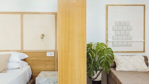A hotel room with a wooden headboard, a bed with white bedding, a marble bedside table, a potted plant, and a framed artwork on the wall. - Exclusive Suite With Terrace By Sorrento Main Square (Sorrento)