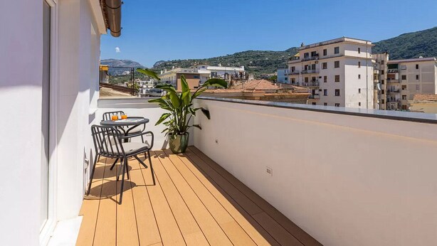 A balcony with a wooden floor, a table with chairs, and a potted plant. - Exclusive Suite With Terrace By Sorrento Main Square (Sorrento)