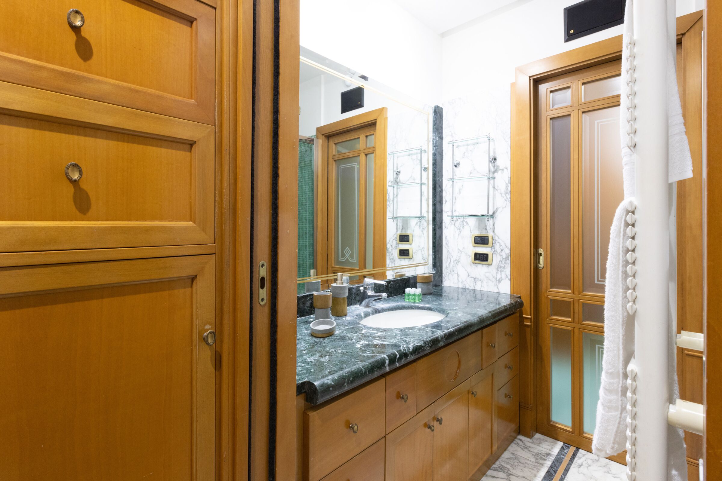 Une salle de bain avec des meubles en bois, un lavabo en marbre et un grand miroir.