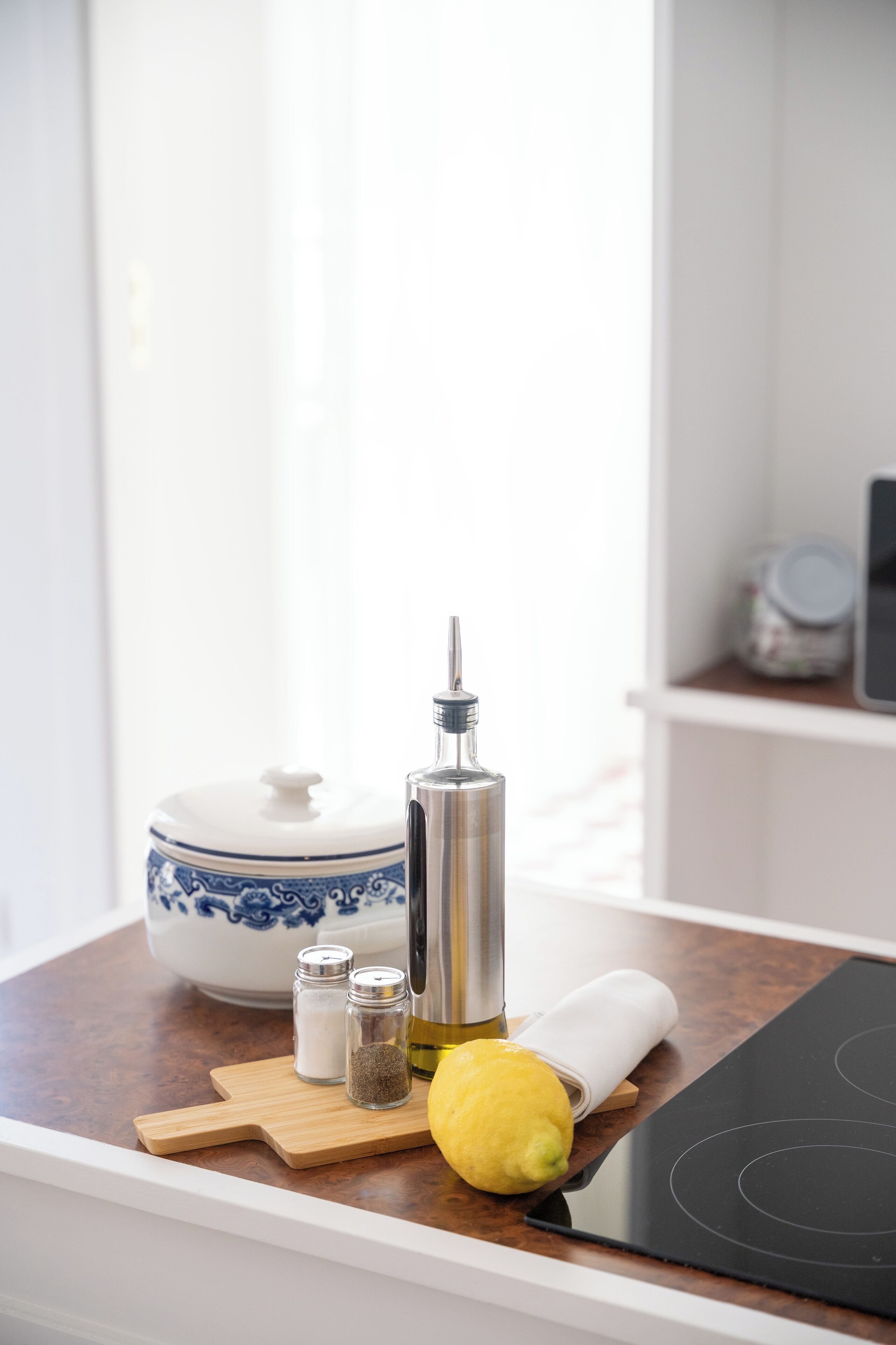 Una encimera de cocina con una tabla de cortar, un limón, saleros y pimenteros, una botella de aceite y una estufa.