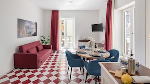 A modern living room with a red sofa, blue chairs, a dining table set, and a checkered floor. - Luxury New Sorrento Home With Terrace - Sleeps 12 (Sorrento)