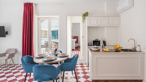 A compact kitchen with a central island, a dining area with blue chairs, and a red and white checkered floor. - Luxury New Sorrento Home With Terrace - Sleeps 12 (Sorrento)