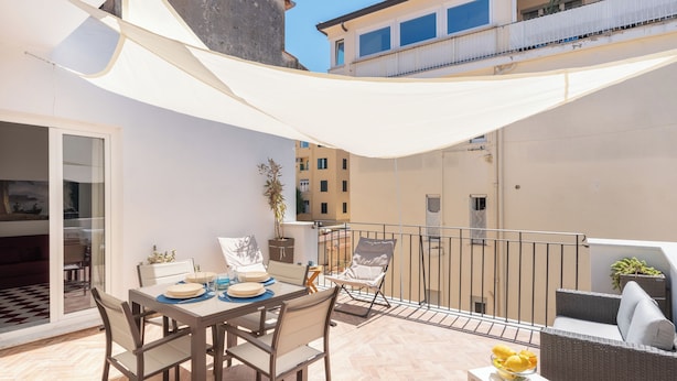 A balcony with a dining table and chairs, a small table with a bowl of fruit, and a potted plant. - Luxury New Sorrento Home With Terrace - Sleeps 12 (Sorrento)