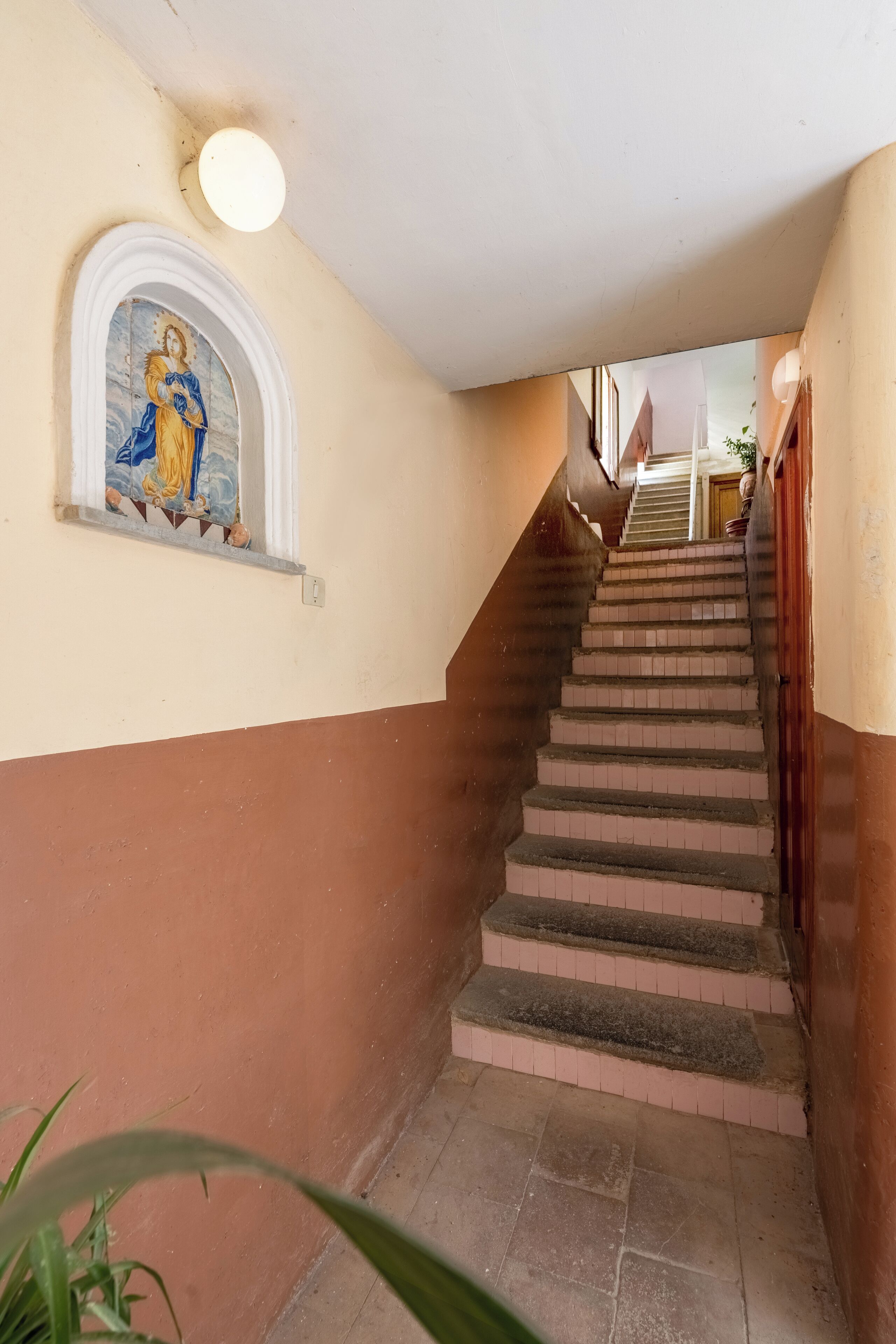 A staircase with a mural, a light fixture, and a potted plant.