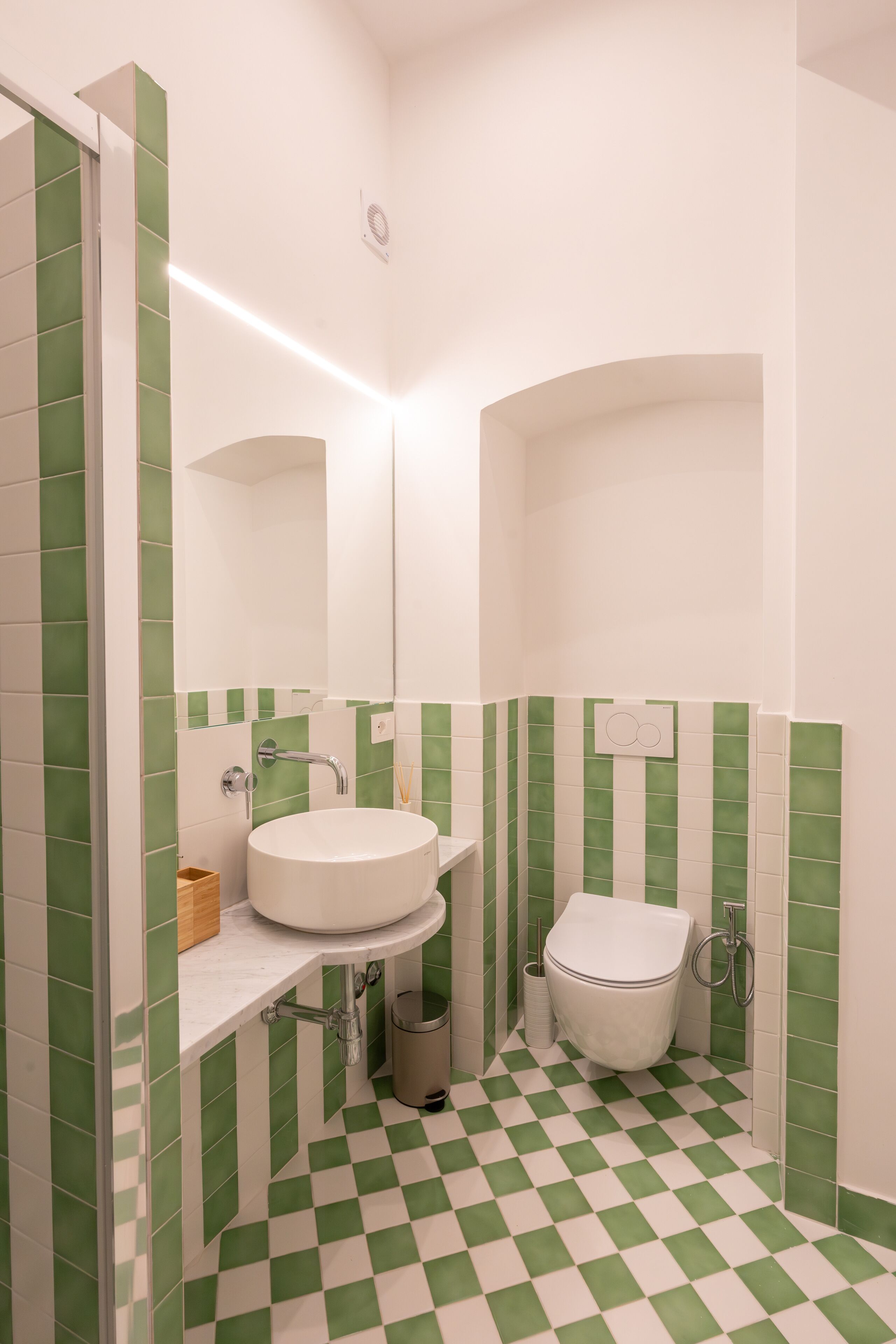 Un bagno con un lavandino bianco, un water e un pavimento a scacchi verdi.