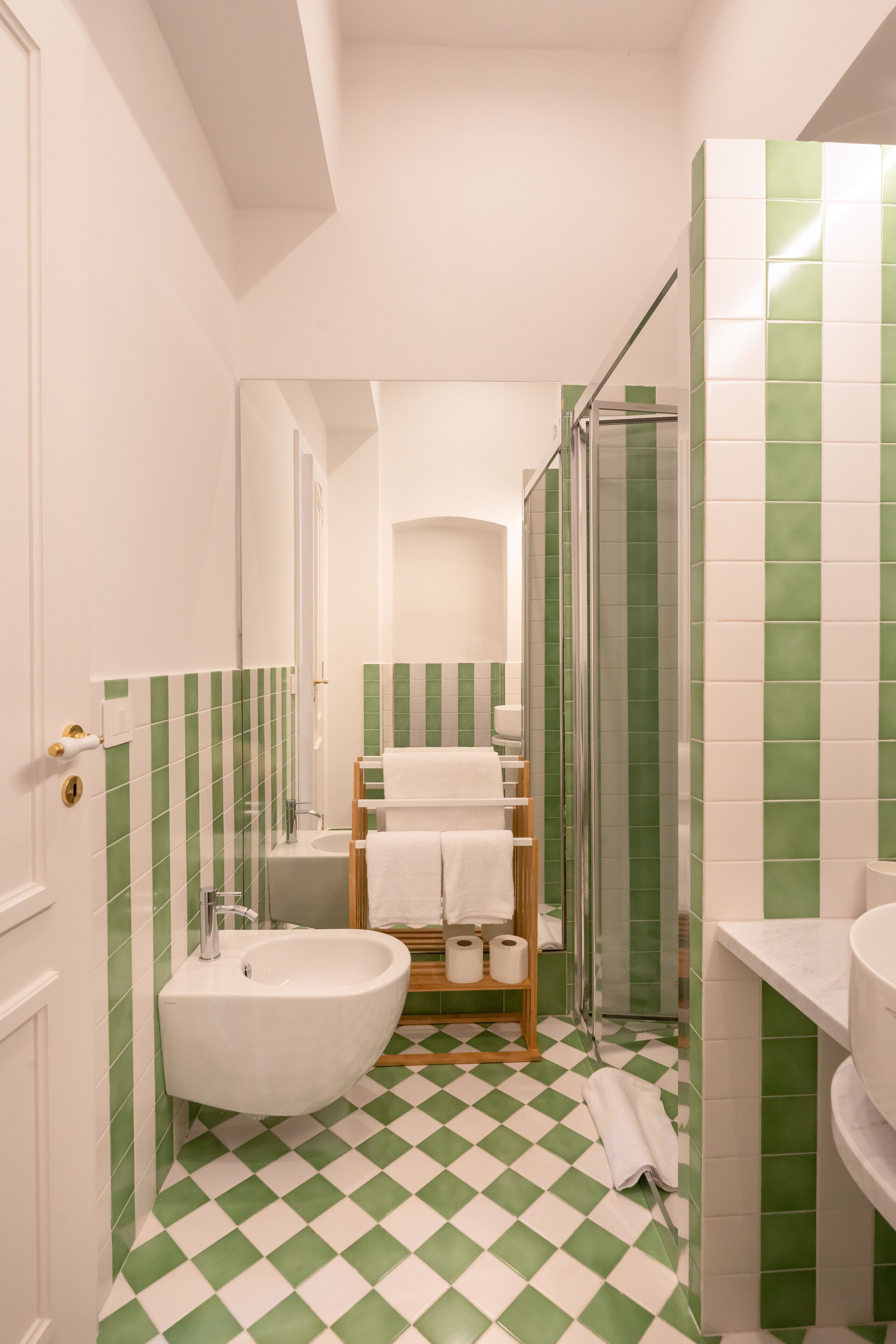 A bathroom with a checkered floor, a sink, a bidet, and a shower area.