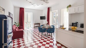A room with a checkered floor, a dining area with blue chairs, a red sofa, and a kitchen area with a microwave and a sink. - Lux Family Home In Sorrento With Terrace/Solarium (Sorrento)