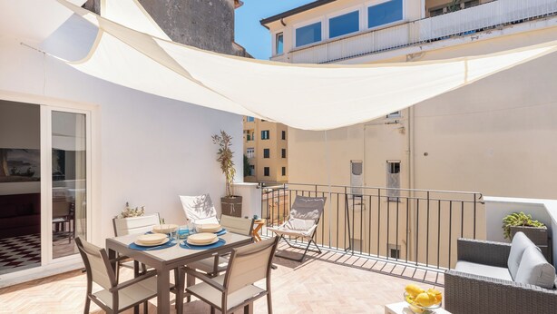 A balcony with a dining table and chairs, a small table with a bowl of fruit, and a potted plant. - Lux Family Home In Sorrento With Terrace/Solarium (Sorrento)