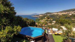 A swimming pool with a wooden deck and a view of the sea and a distant mountain. - Villa Panorama With Private Pool & View (Massa Lubrense)