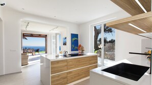 A modern kitchen with a large island, wooden cabinetry, and a black sink. - Villa Panorama With Private Pool & View (Massa Lubrense)