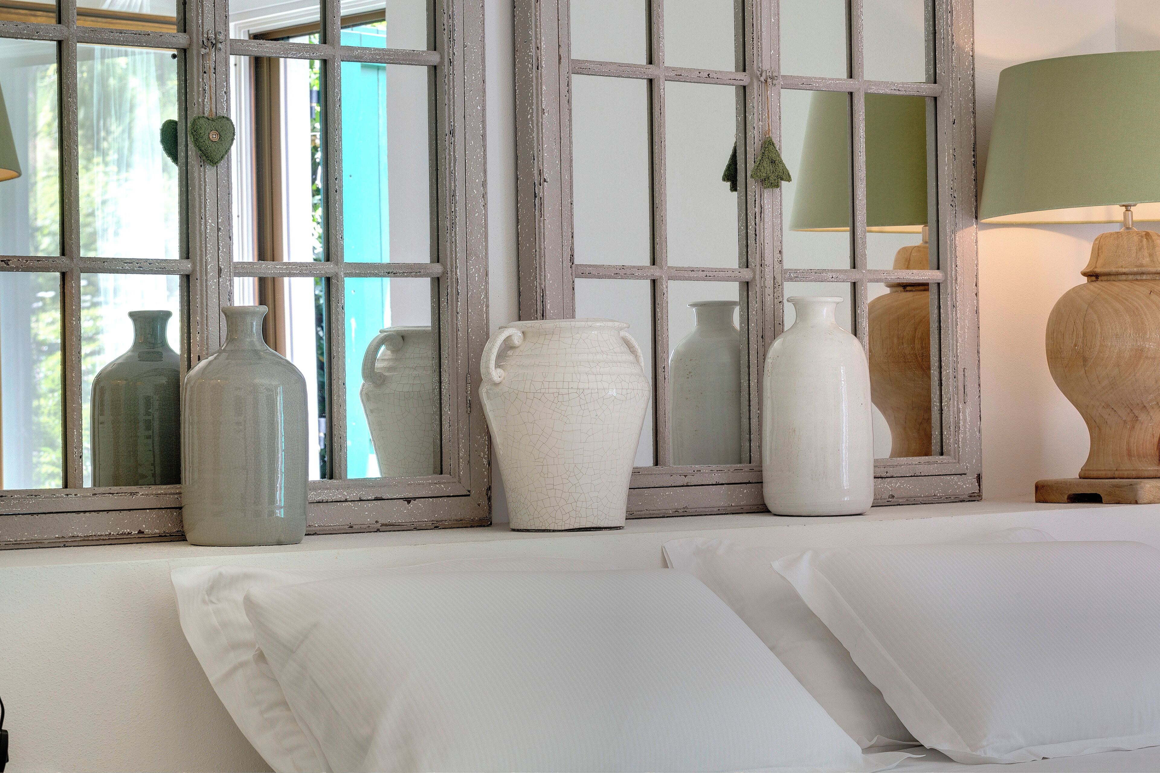 A room with a window displaying various vases and a lamp.