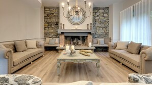 A spacious living room with a fireplace, two sofas, a coffee table, and a chandelier.