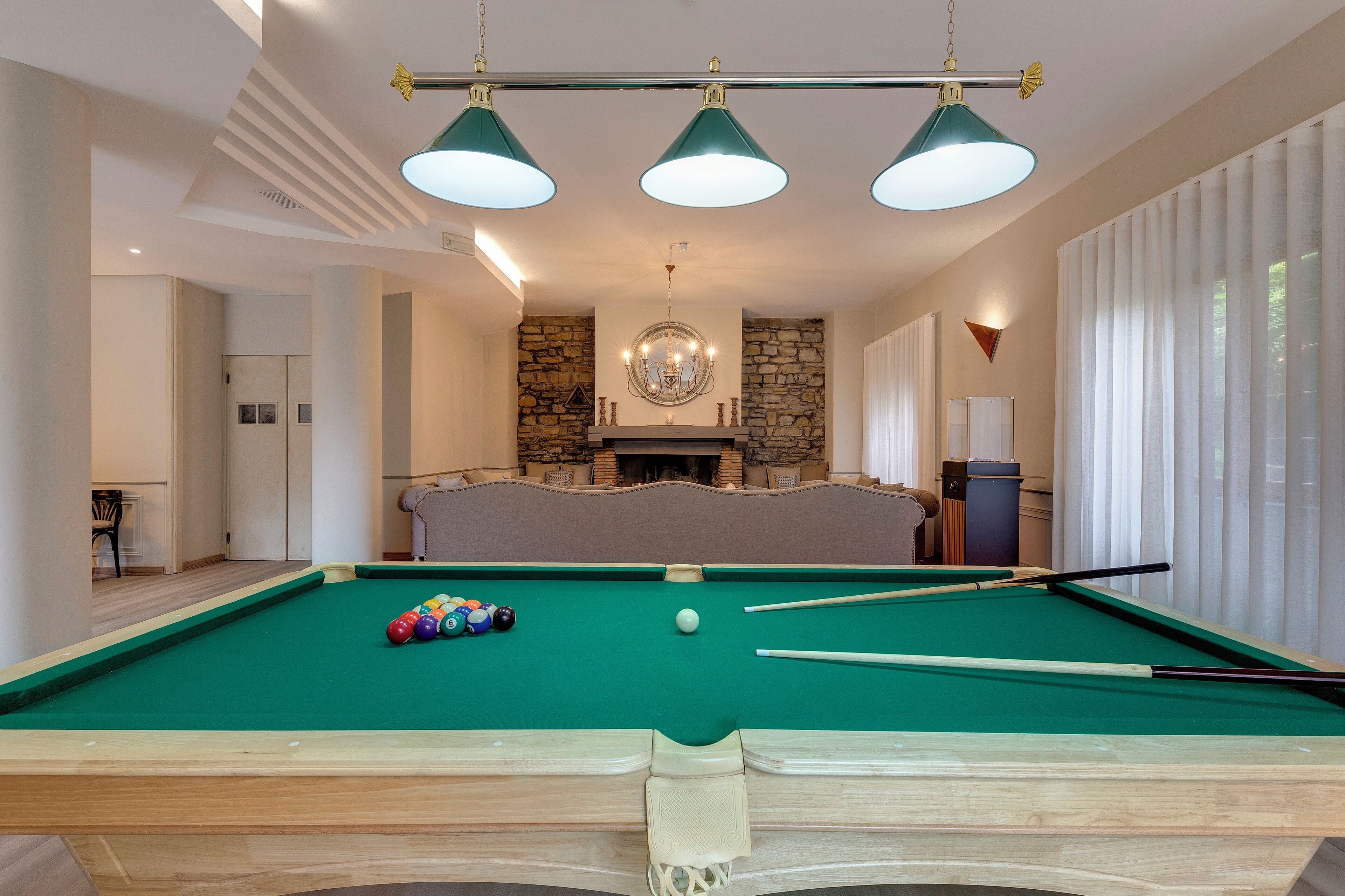A pool table with balls, a fireplace, and a stone wall.