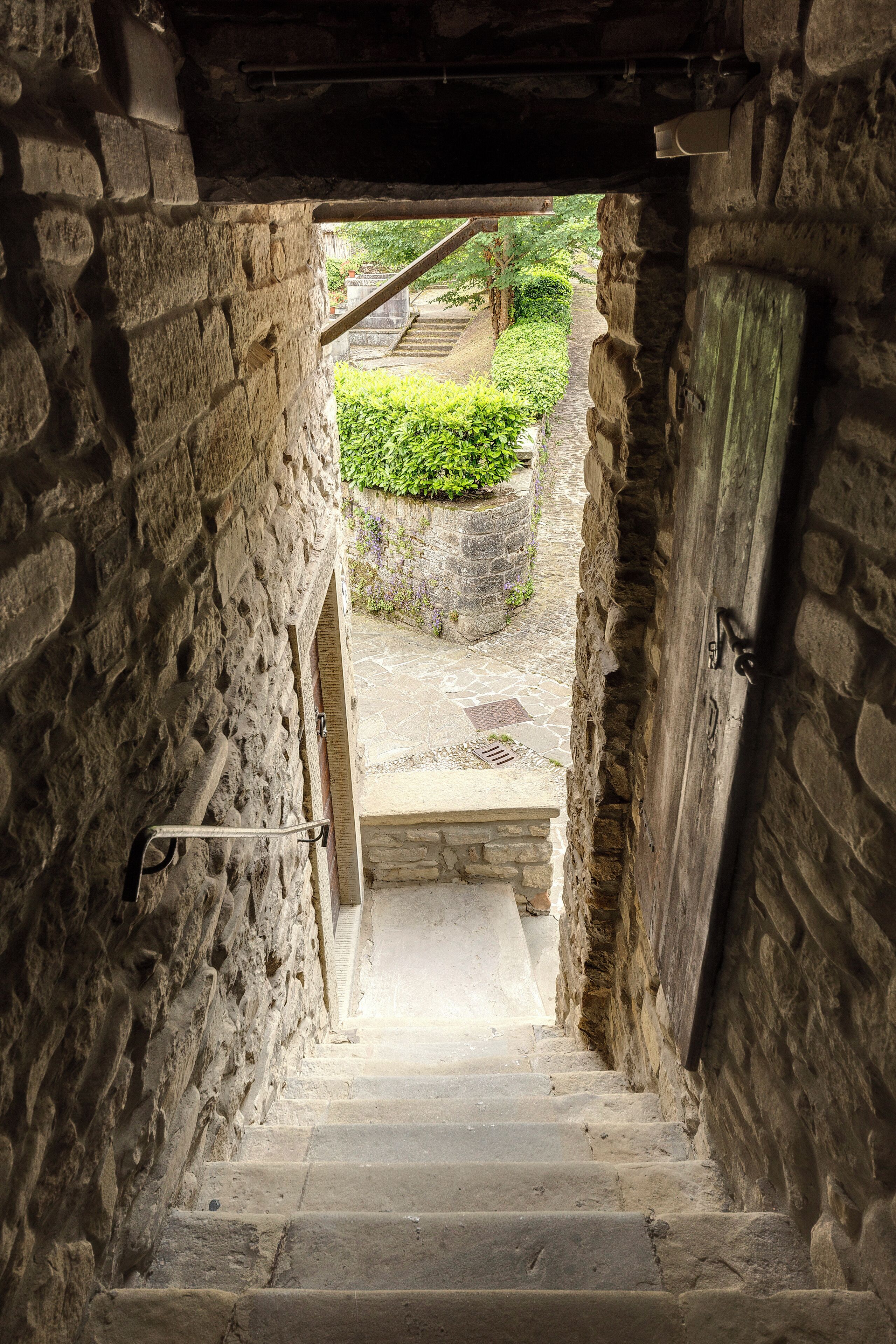 Un escalier en pierre mène à un espace extérieur agrémenté d’un jardin et d’un mur en pierre.