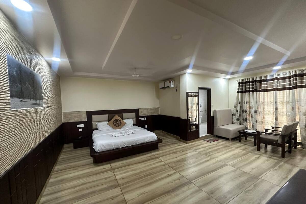 A hotel room with a large bed, a sofa, a coffee table, and a TV.