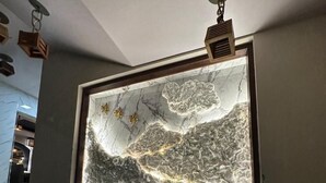 A staircase leading to a room with a large, illuminated marble wall. - Hotel Anant Restaurant And Bar (Balh)