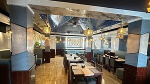 A restaurant with a long counter, booths, and a high ceiling with a skylight. - Hotel Anant Restaurant And Bar (Balh)