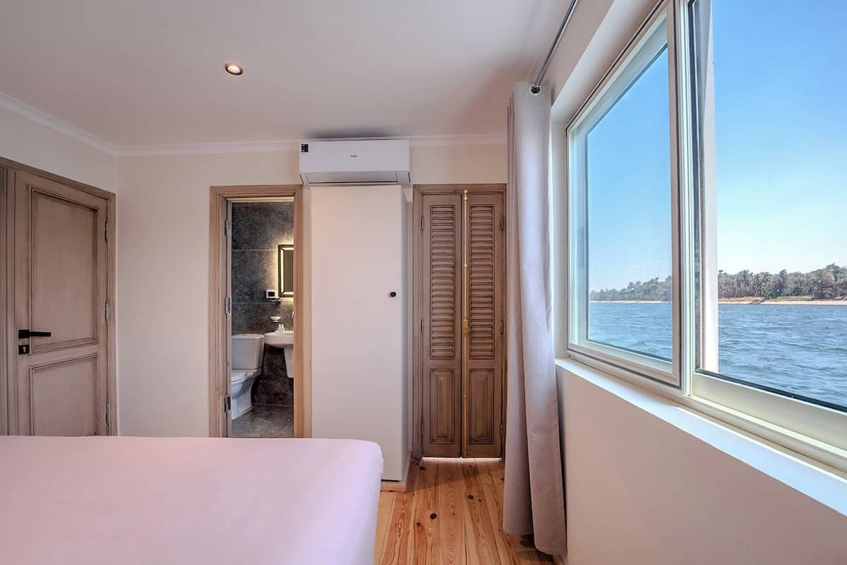 Ein Hotelzimmer mit Bett, Bad, Kleiderschrank und Meerblick.