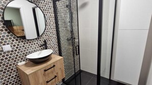 A modern bathroom with a round mirror, a wooden vanity, a black shower enclosure, and a tiled floor. - Cozy 1-bedroom apartment in lovely Warszawa with WiFi (Warszawa)