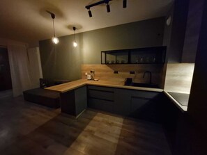 Una cocina moderna con encimera de madera, electrodomésticos integrados e iluminación colgante.