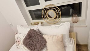 A bedroom with a bed, pillows, a window with blinds, a woven wall hanging, and a small shelf with a vase. - Cozy 1-bedroom apartment in lovely Warszawa with WiFi (Warszawa)