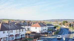 A residential street with houses, a curved road, and a clear sky. - Host Stay The Parade View (Whitby)