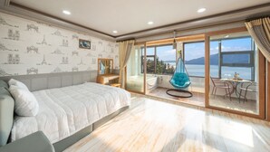 Un dormitorio amplio con una cama grande, una zona de estar con una hamaca colgante y un balcón con vistas al mar.