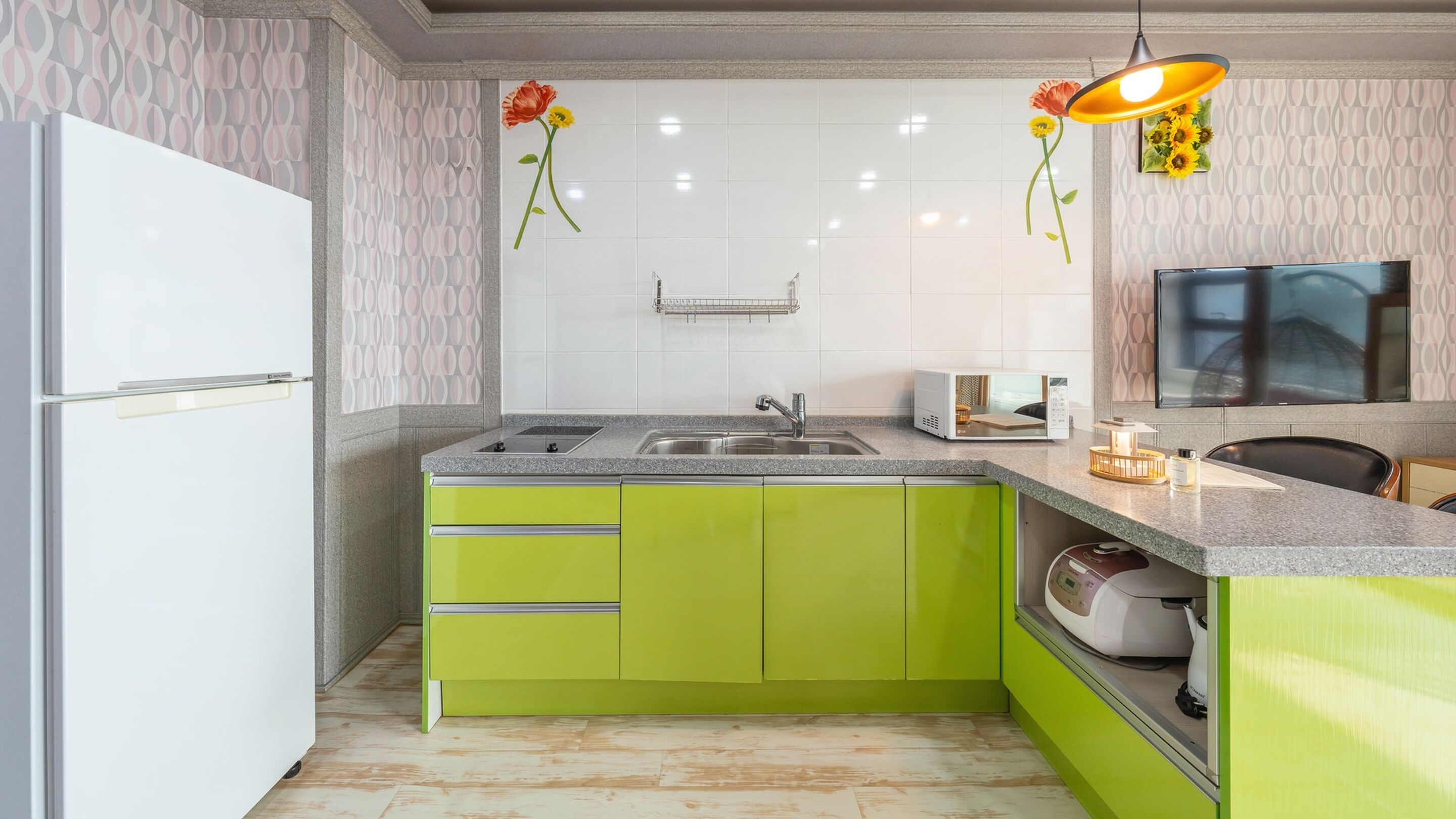 A kitchen with green cabinets, a white refrigerator, a microwave, and a sink.
