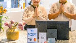 Un comptoir d’accueil avec un panneau indiquant que les cartes VISA et MasterCard sont acceptées, un terminal de paiement électronique et une plante décorative.