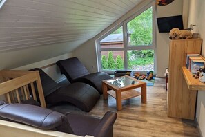 Relax in this inviting room with a comfortable sofa and armchair, facing a lush garden view.