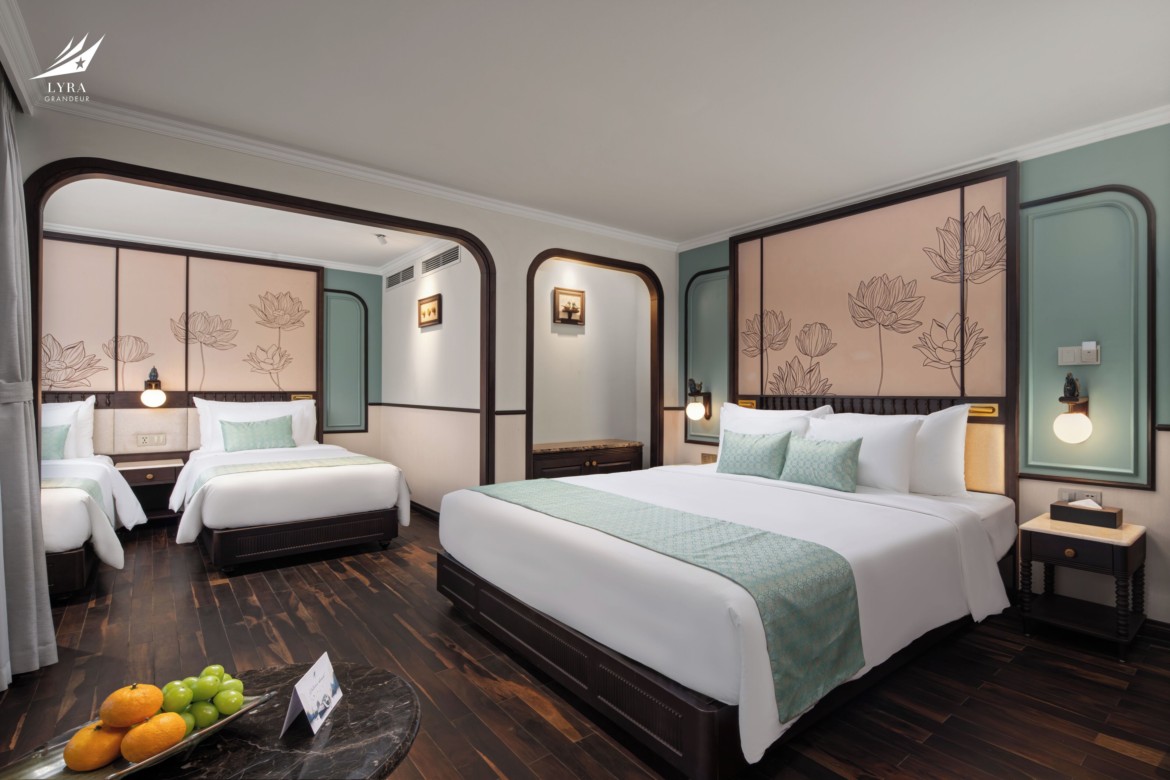 A hotel room with a large bed, two smaller beds, wooden flooring, and floral wall decor.