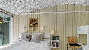 A bedroom with a bed, bedside lamps, a bookshelf, a chair, and a wall tapestry. - "Quiana" - 2km from the sea by Interhome (Pandrup)