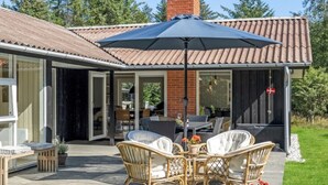 A covered patio with wicker furniture, a table, and a large umbrella. - "Quiana" - 2km from the sea by Interhome (Pandrup)