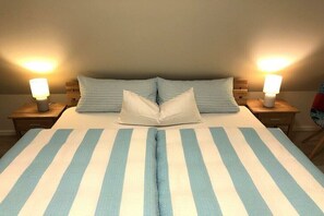Restful retreat with a neatly made bed, two pillows, and bedside lamps.