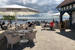 Enjoy waterfront dining at Bayreuther with tables under shaded umbrellas.