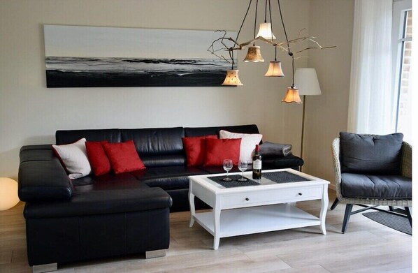 Relax in style with a comfortable black leather sofa, a coffee table, and a wicker chair.