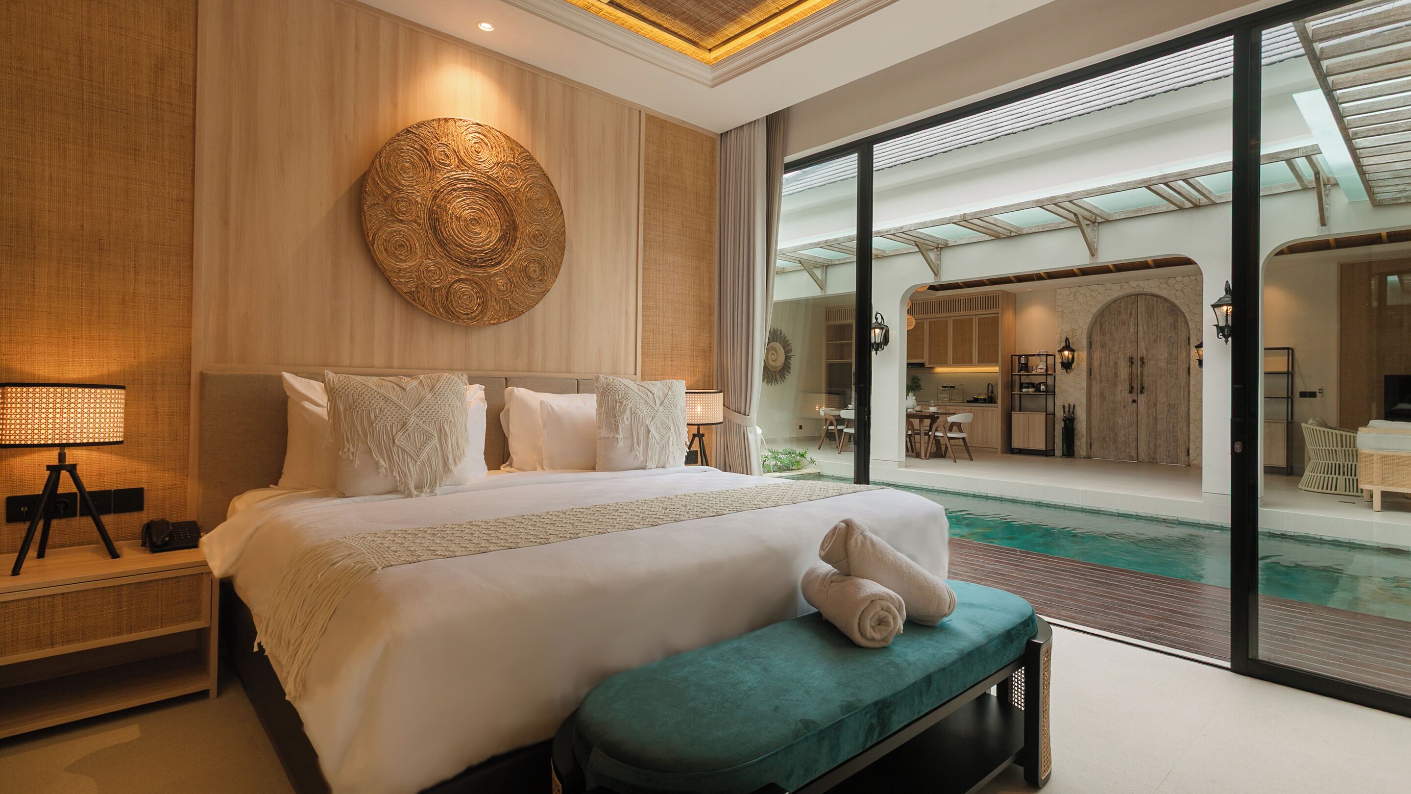 A modern hotel room with a large bed, a view of the pool, and a kitchenette.