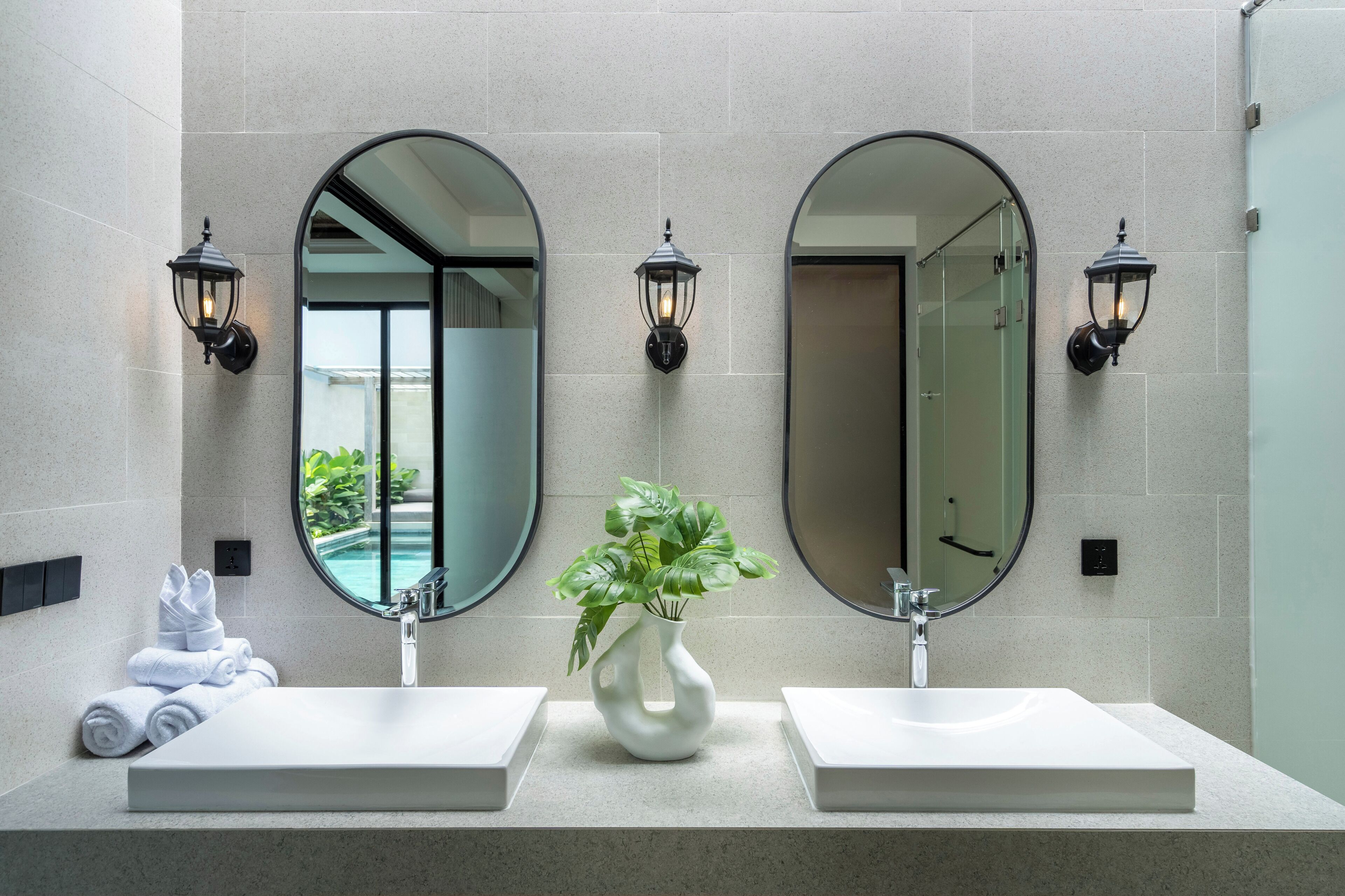Un bagno con due lavandini, uno specchio grande e applique a parete.