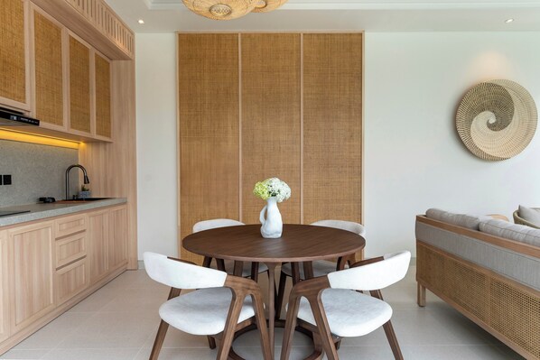 A modern kitchen with wooden cabinets, a round dining table, and white chairs.