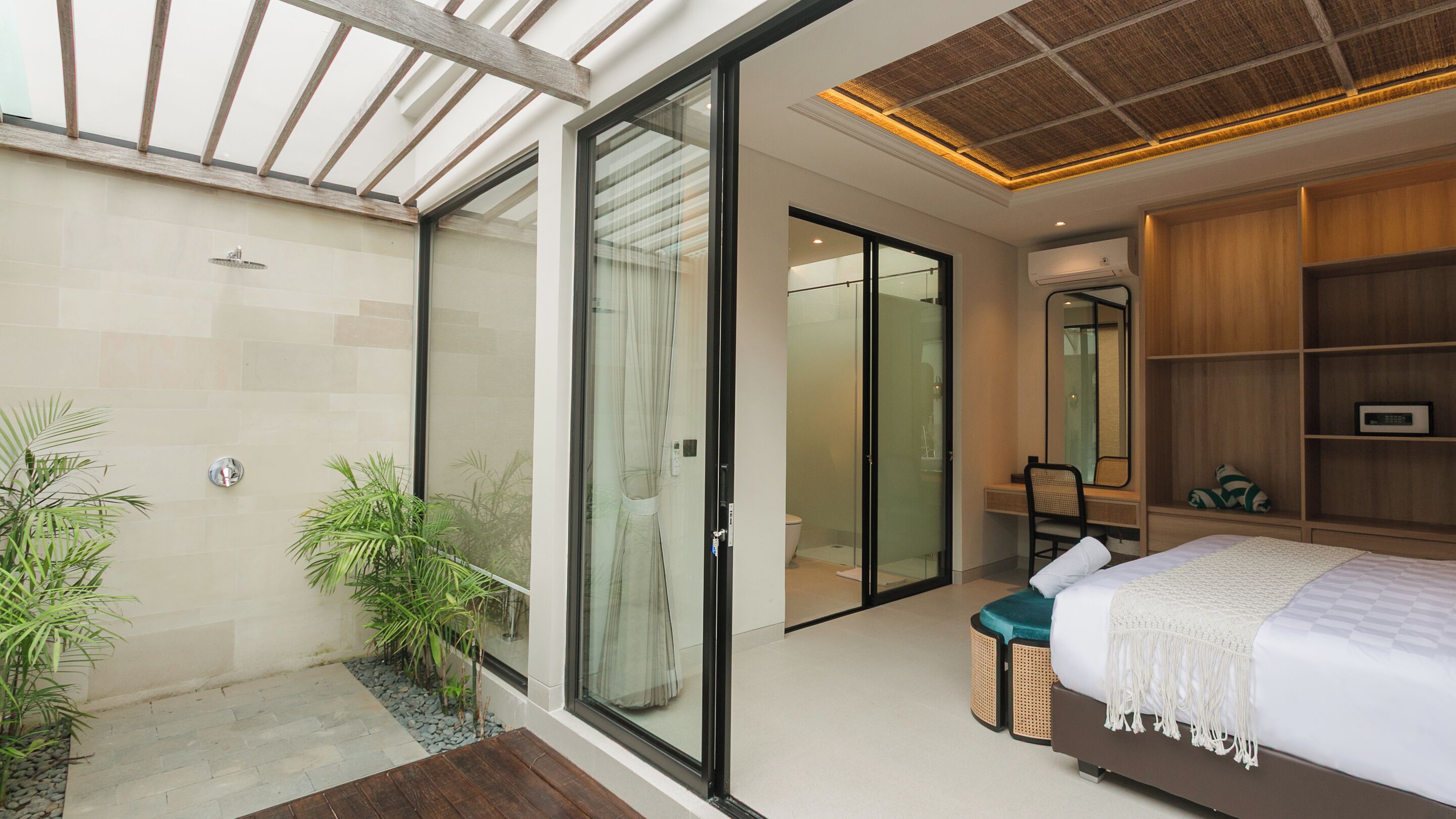 A modern bedroom with a large bed, a walk-in closet, and a glass shower enclosure.