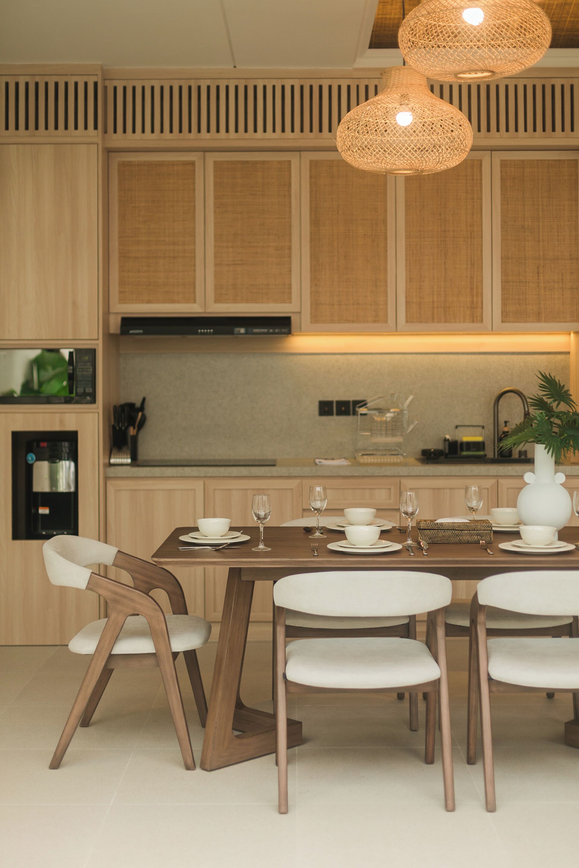 A modern kitchen with wooden cabinets, a built-in microwave, and a dining area with a wooden table and chairs.