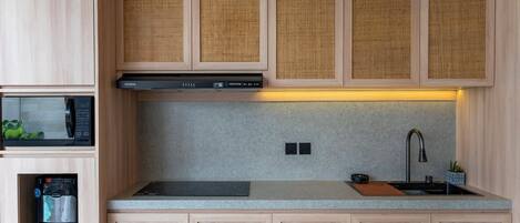Una cocina moderna con armarios de madera, microondas integrado, cafetera y pileta de acero inoxidable.