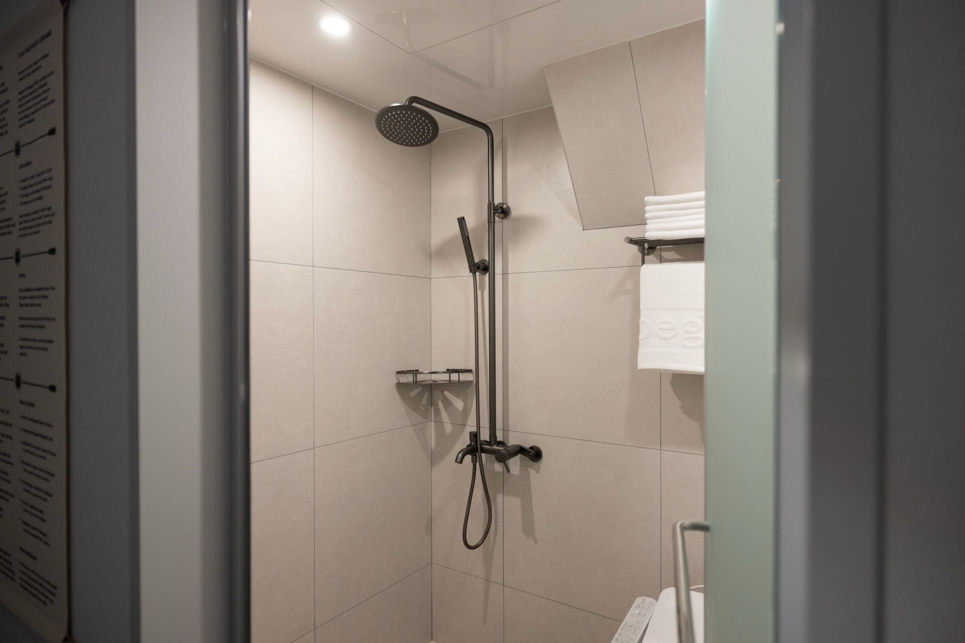 A modern shower with a handheld showerhead and a fixed overhead showerhead.