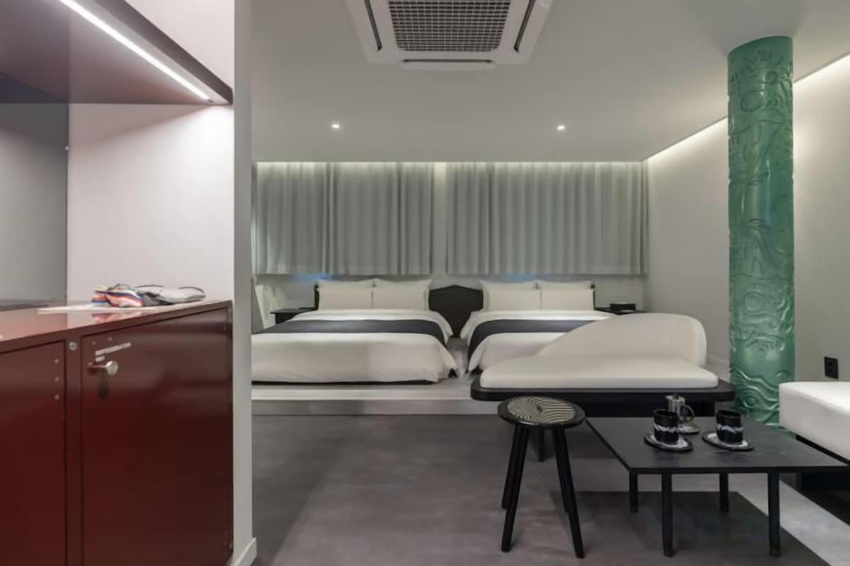 A modern hotel room with a bed, bedside table, and a desk with a chair.