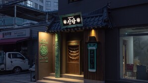 Un restaurante con arquitectura coreana tradicional, que presenta un letrero con la palabra 'Passport' y un emblema verde.