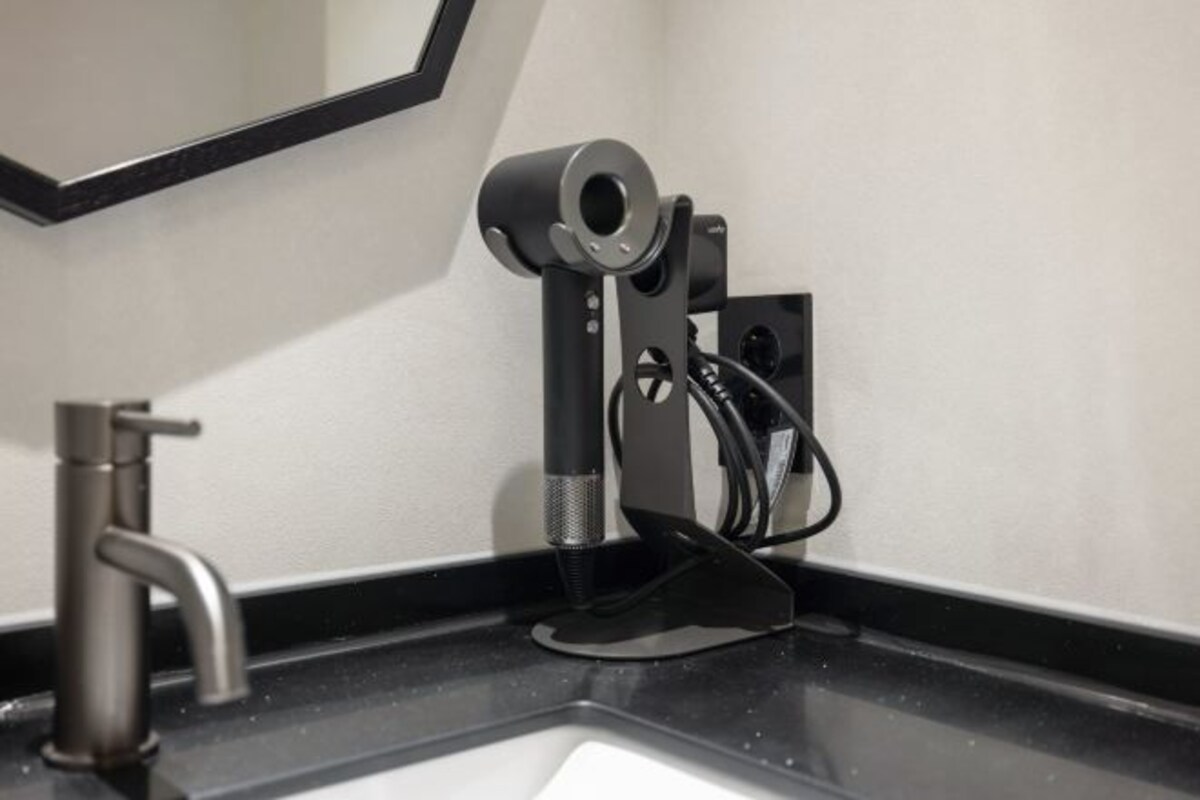 Una cámara web montada sobre un soporte negro, junto a un lavabo de baño con un grifo moderno.
